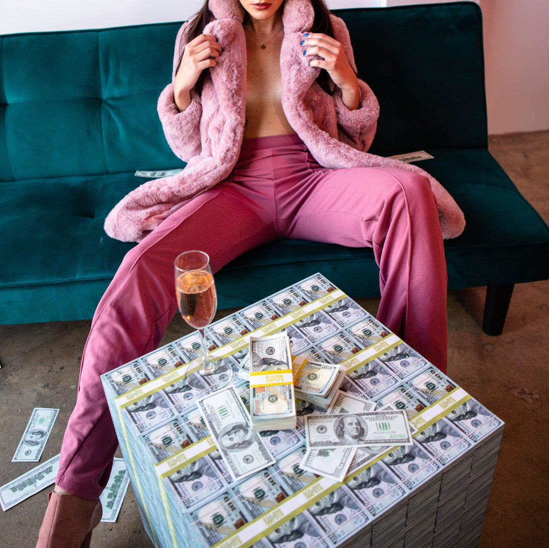 woman in pink on green sofa looking at a center cube money table